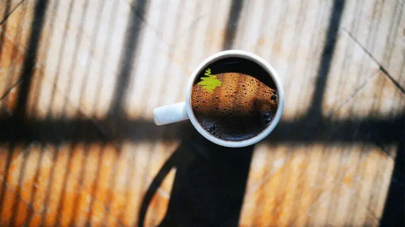 A cup of coffee on a flat surface in sunlight