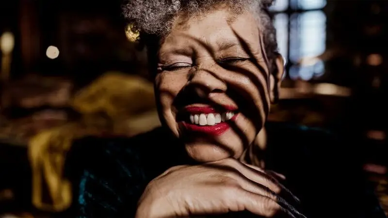 older Black women smiling at the camera with her eyes closed