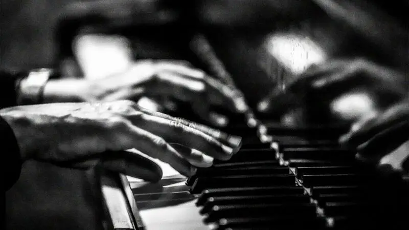 black and white photo of hands on piano keys