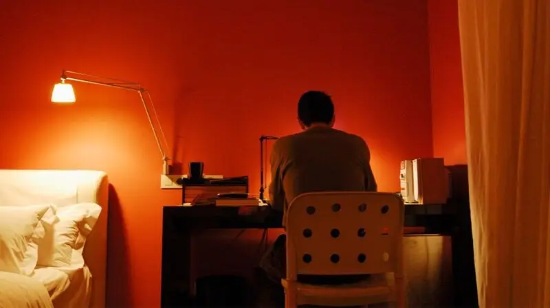 A person sitting at their desk with their back turned against the camera