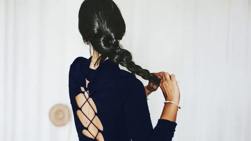 A woman braids her long hair