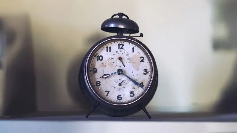 An old analog alarm clock showing twenty past eight as the time