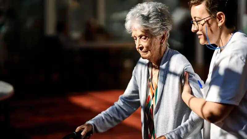 caregiver supporting older woman as she walks