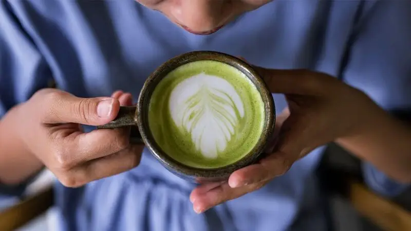 hands holding a cup of matcha latte