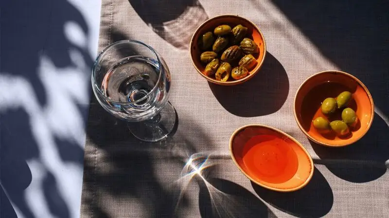 bowls of green olives and glass of white wine