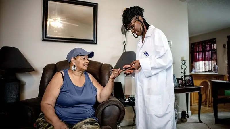 young Black female doctor performing finger prick test on older Black female patient