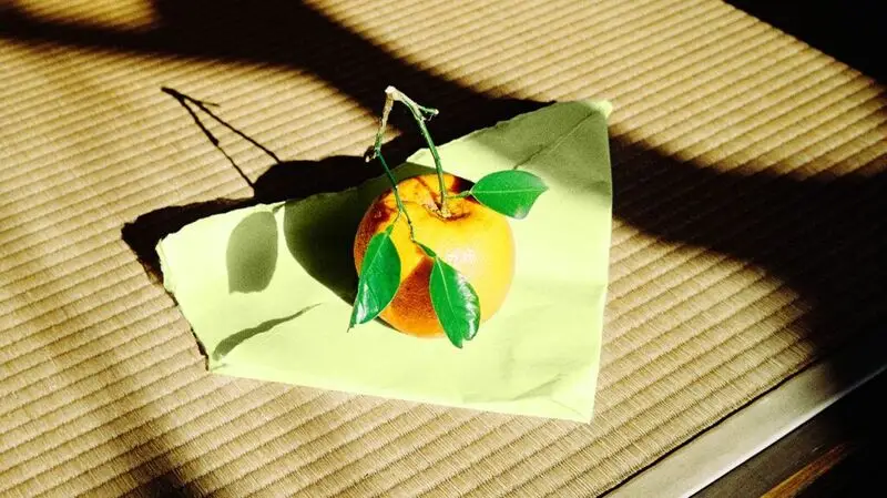 photo of orange fruit on slip of paper on tatami mat