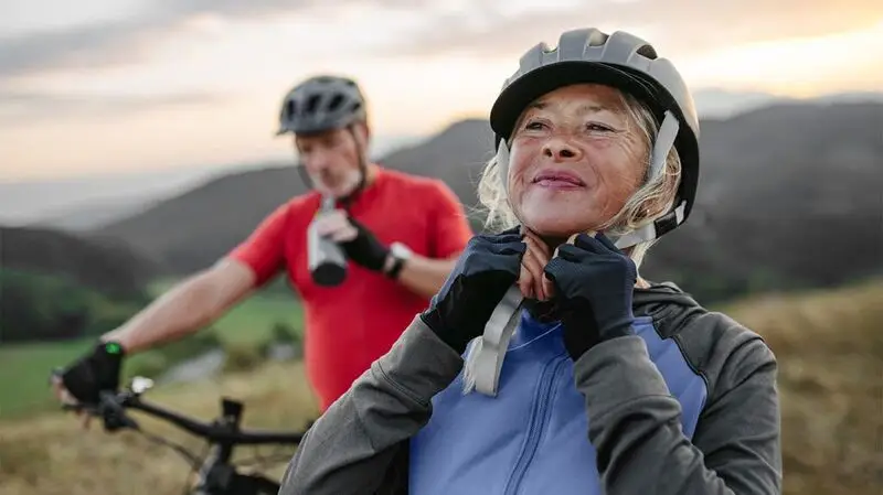 older couple cycling surrounded by hills