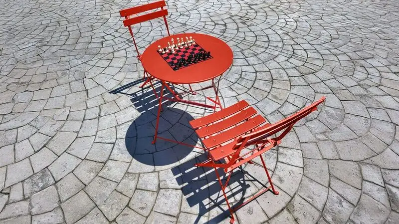 A chess set on a cafe table and two sets of chairs