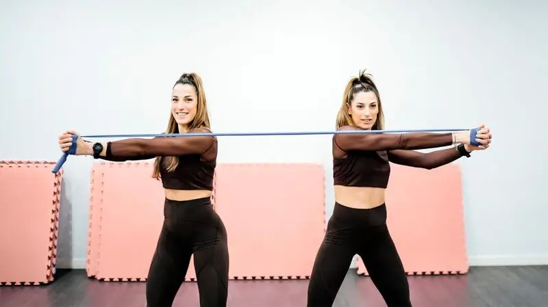 Two twins exercising with a resistance band pulling it in the opposite direction