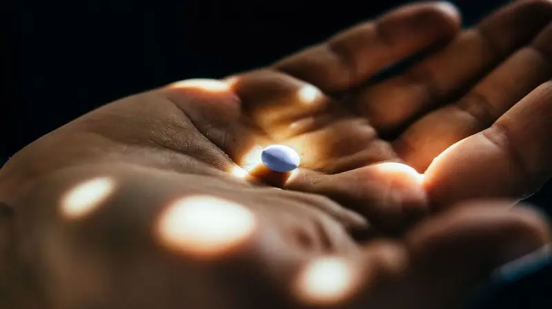 A person holding a vitamin D capsule in the middle of their palm