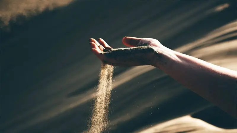 Sand slipping through someone's fingers