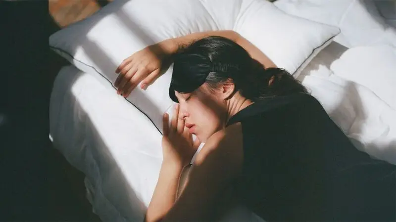 young woman asleep face down on bed