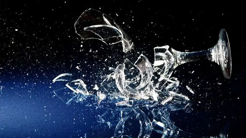 A wine glass shattering, representing the bad habit of heavy drinking of alcohol