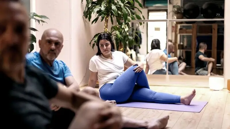 person in yoga class with bended knee doing hip stretch