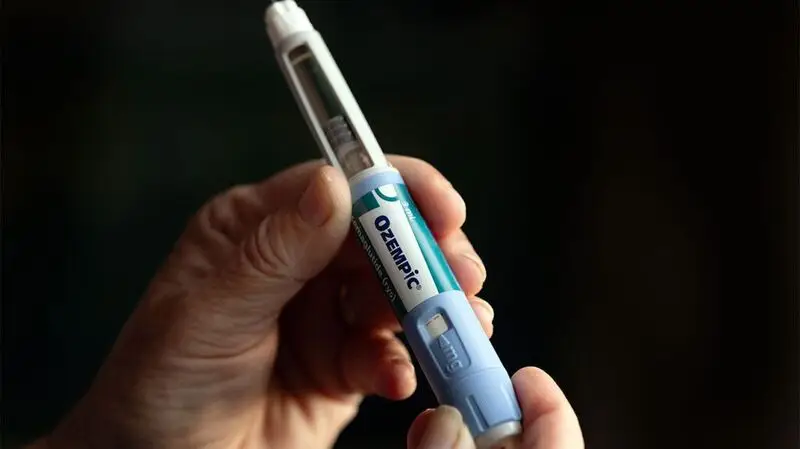 A person holding an Ozempic pen, the active ingredient of which is semaglutide