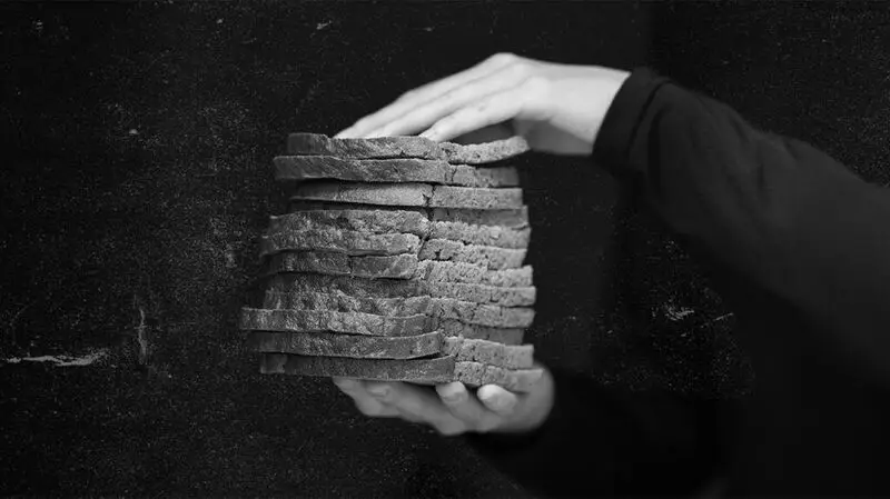 A person holds wholegrain slices of bread stacked on top of each other between their hands