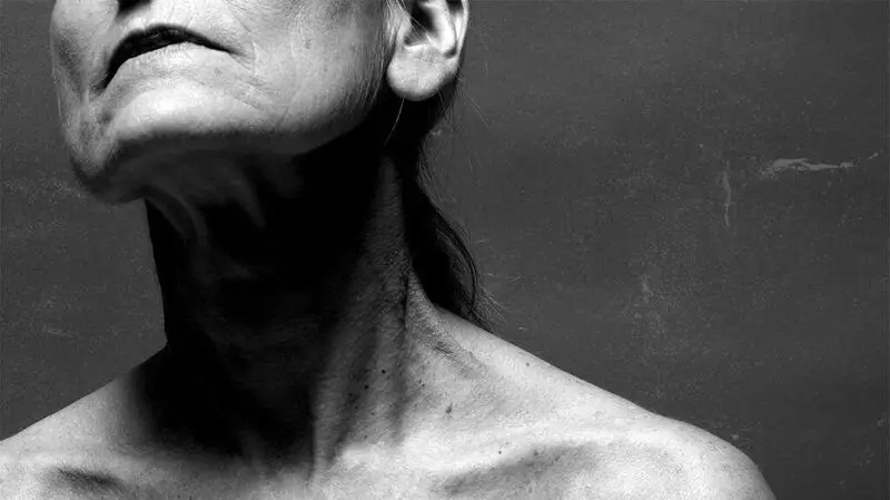 A close up of the shoulder, neck and face of an older adult woman
