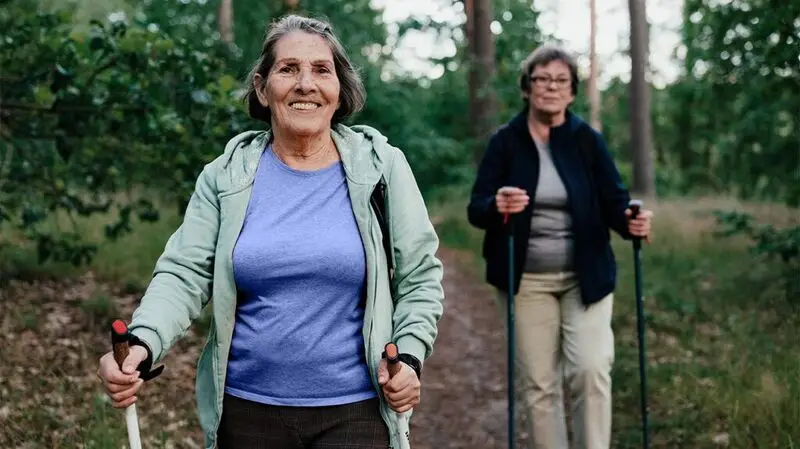 two older white women trekking through the woods