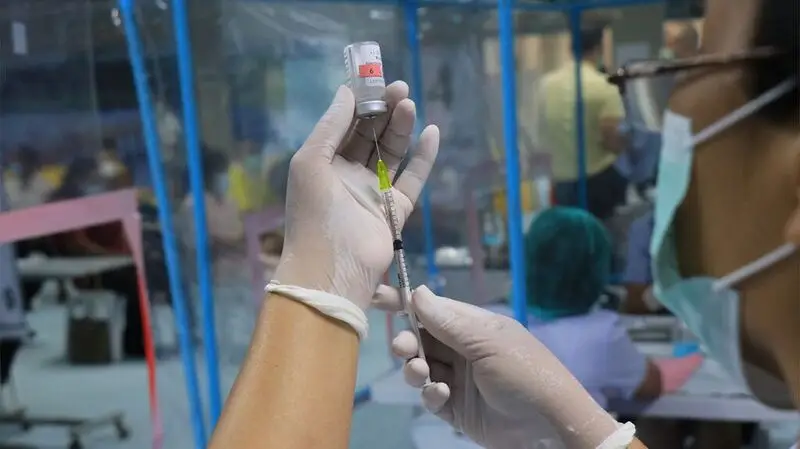 hands in surgical gloves extracting vaccine dose from vial
