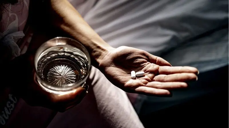 two white pills on person's outstretched palm