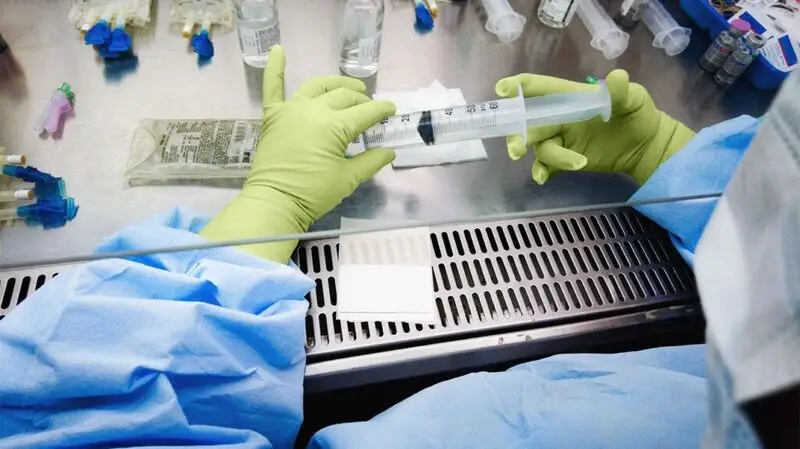 A medical professional prepares a chemotherapy mix with a syringe in hand in a sterile healthcare environment