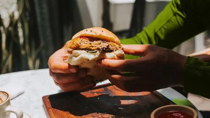 A person holding a plant-based chicken burger between their hands