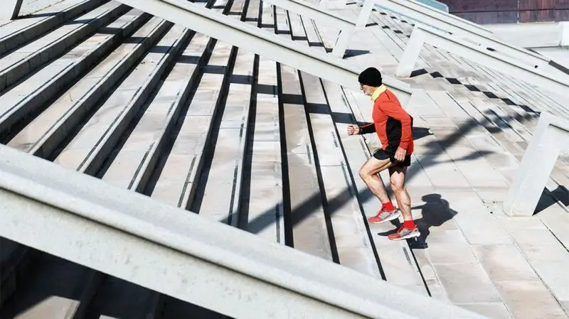 An older adult runs up stairs outside in running gear