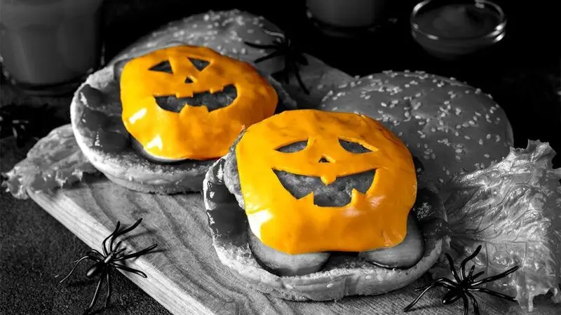 color pop photo emphasizing burger cheese slices cut in the shape of jack o lanterns