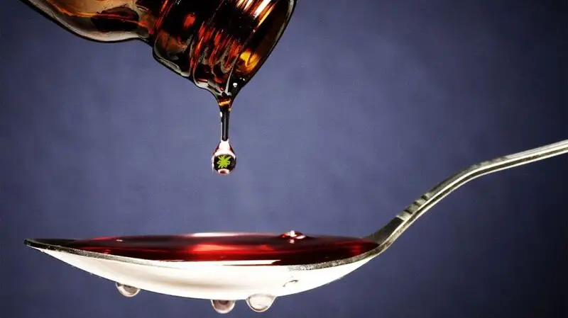 close-up of cough syrup dripping into teaspoon