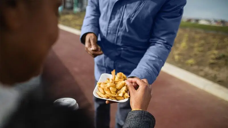 person offering a plate of chips to someone else