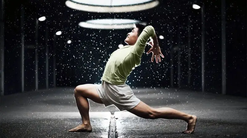 A man doing a yoga pose reminiscent of a warrior pose with an arm extension towards the back, his elbows bent