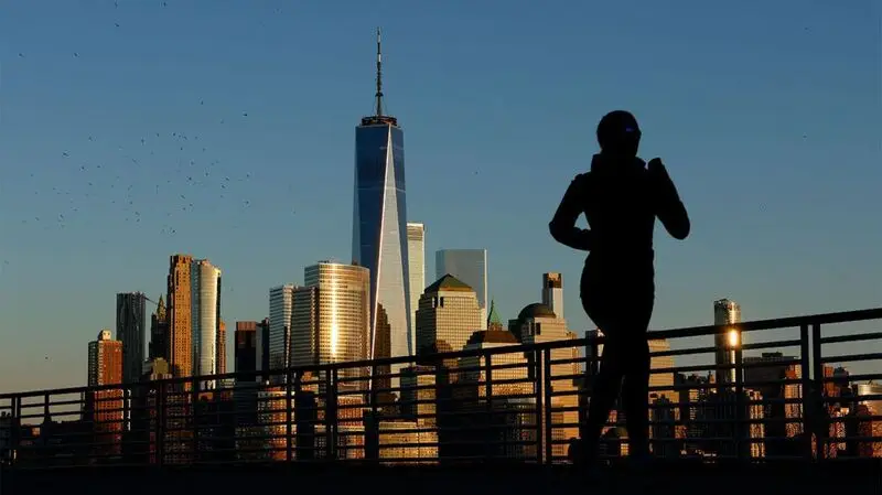 A person running on abridge against a backdrop of buildings on the New York skyline