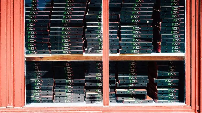 Dozens of cardboard pizza boxes stacked up on top of each other