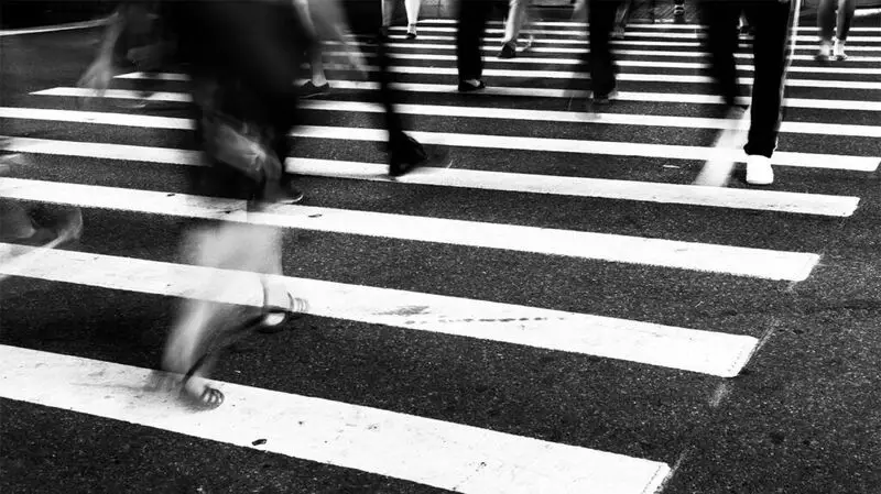 black and white photo of feet on a zebra crossing