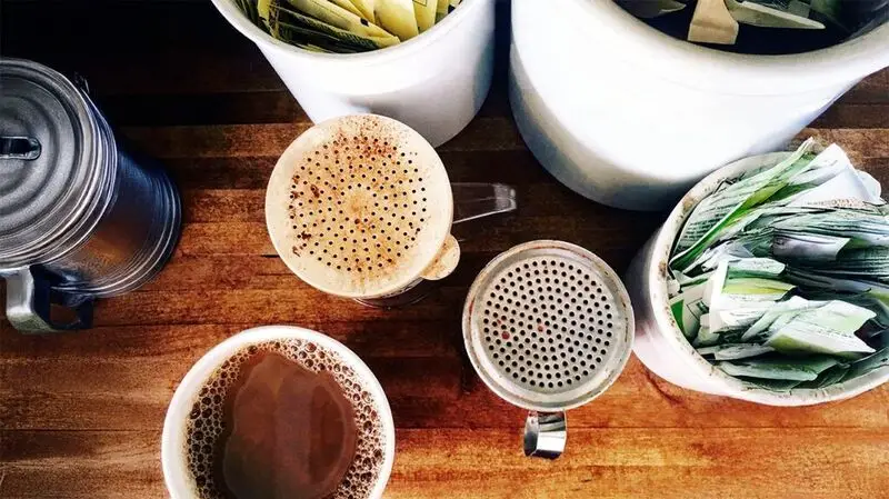Packets of artificial sweeteners in mugs on a coffee making station on a wooden table