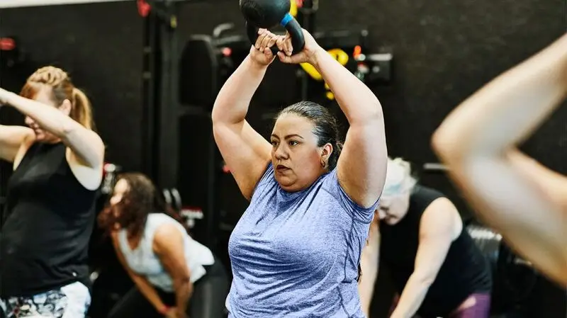 A middle-aged woman lifting weights during a workout class