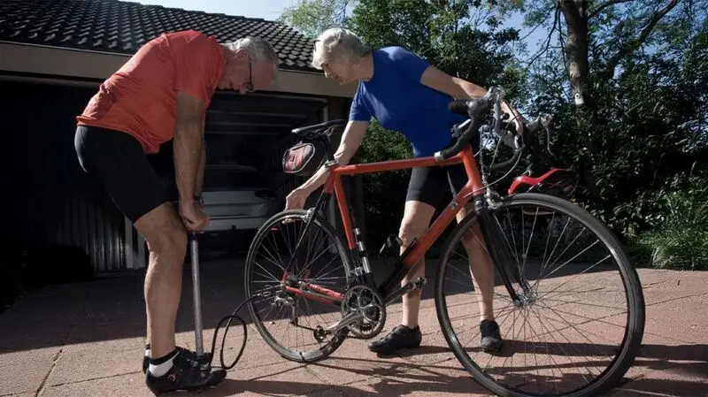An older adult couple fixing a bicycle outside