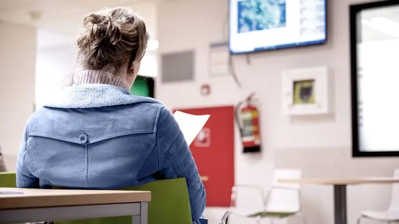 older woman reading a chart in hospital, seen from the back