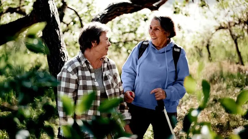 two older white women hiking in the woods