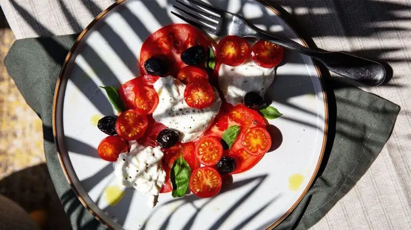 plate of mozzarella, tomatoes, olives, and basil