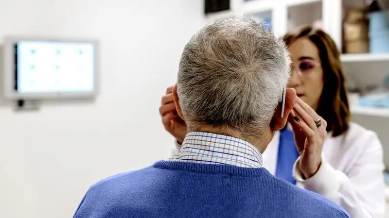 A healthcare professional gives an eye exam to an older adult man