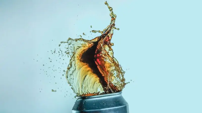A can of an artificially sweetened drink being opened as the liquid bursts out