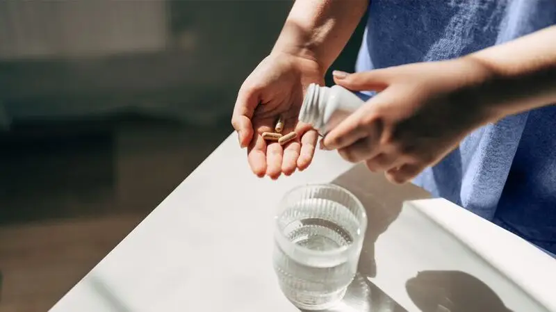 person taking supplements from supplement bottle