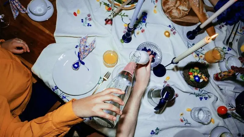hand pouring fizzy drink into glass over celebratory dinner table