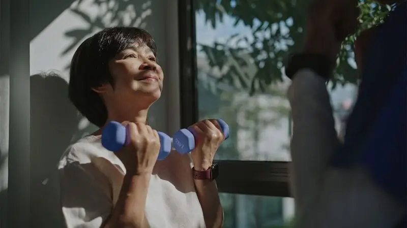 older Asian woman lifting hand weights
