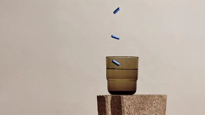 Anti-cholesterol pills falling down into a glass from above