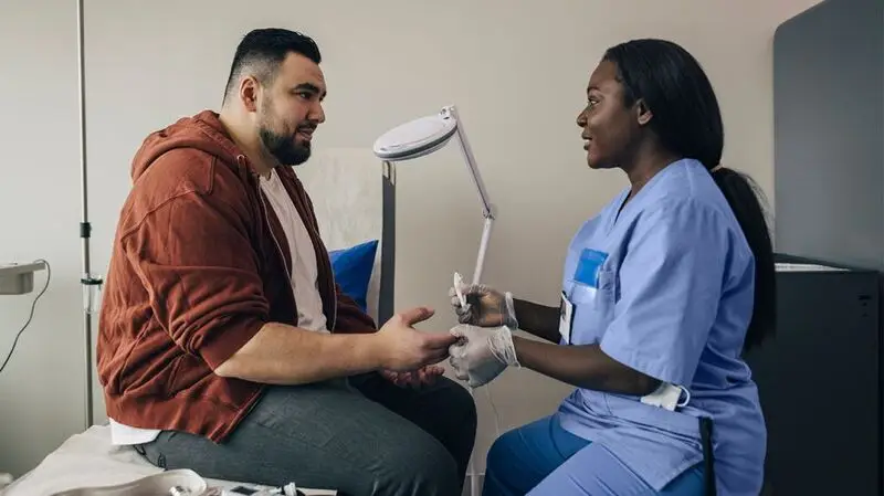 A nurse prepares a patient for a blood test, geting ready to wipe the skin with an alcohol swab