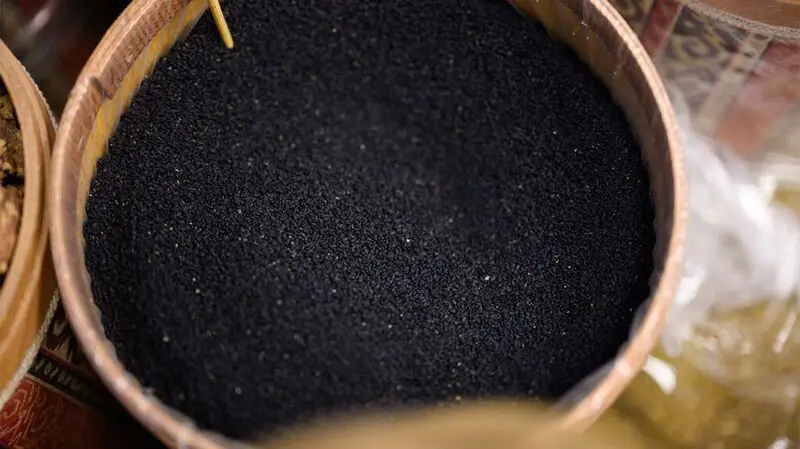 Black cumin seeds in a bamboo circular container