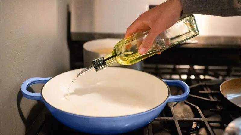 person pouring oil into pan